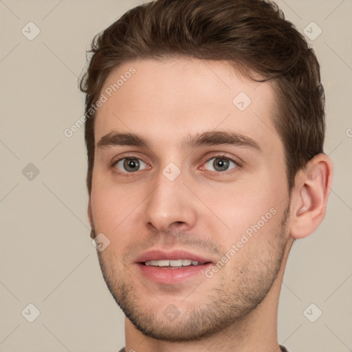 Joyful white young-adult male with short  brown hair and grey eyes