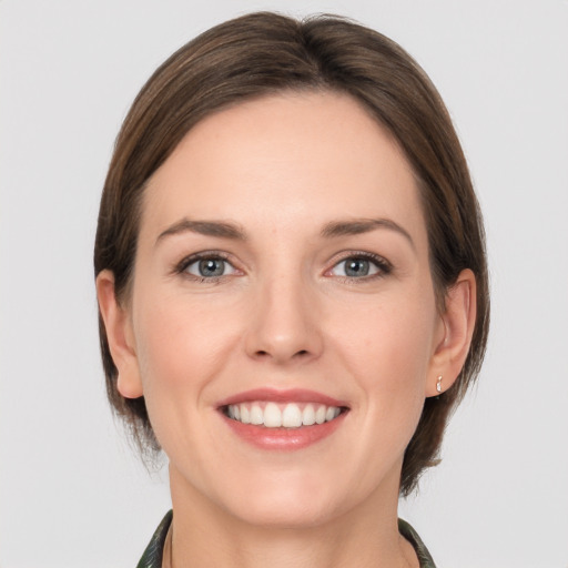 Joyful white young-adult female with medium  brown hair and grey eyes