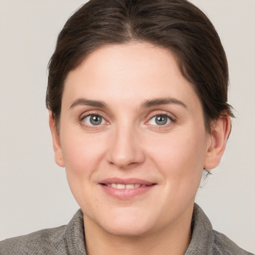 Joyful white young-adult female with medium  brown hair and grey eyes