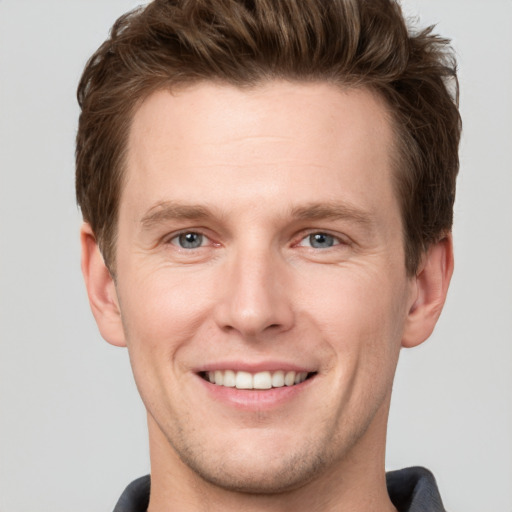 Joyful white young-adult male with short  brown hair and grey eyes