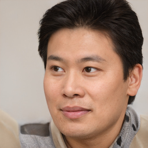 Joyful asian adult male with short  brown hair and brown eyes