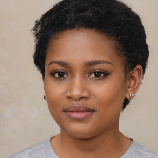 Joyful black young-adult female with short  black hair and brown eyes