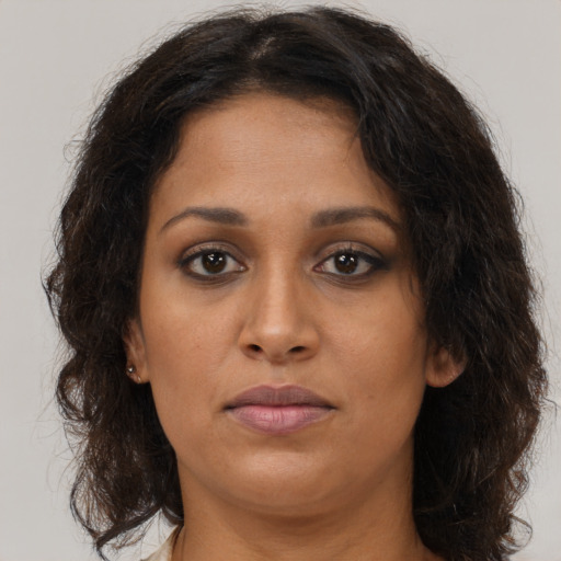 Joyful black young-adult female with long  brown hair and brown eyes