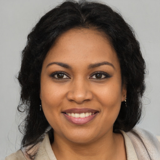 Joyful black young-adult female with long  brown hair and brown eyes