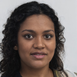 Joyful black young-adult female with long  brown hair and brown eyes