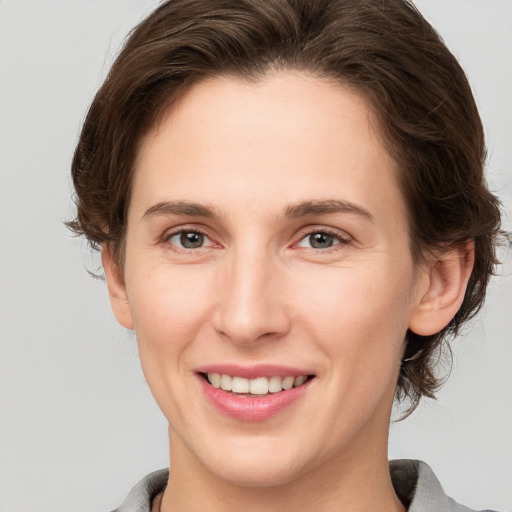 Joyful white young-adult female with medium  brown hair and grey eyes