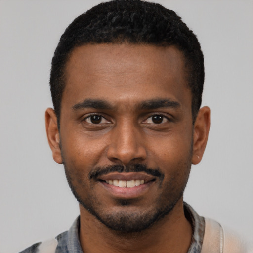 Joyful black young-adult male with short  black hair and brown eyes