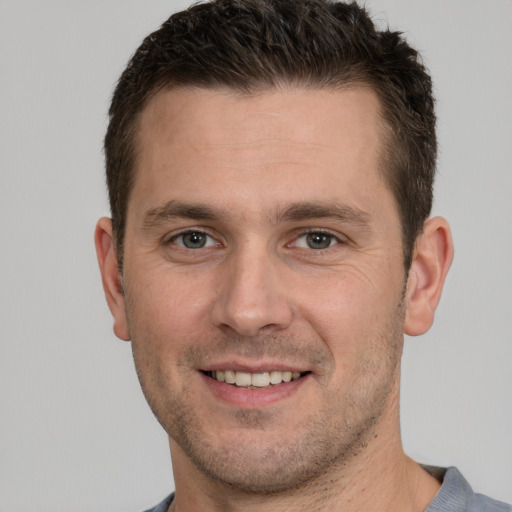 Joyful white young-adult male with short  brown hair and grey eyes