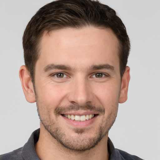 Joyful white young-adult male with short  brown hair and grey eyes