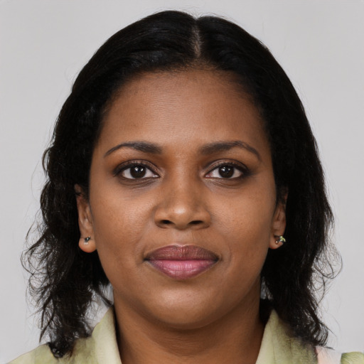 Joyful black young-adult female with long  brown hair and brown eyes