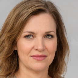 Joyful white adult female with medium  brown hair and green eyes