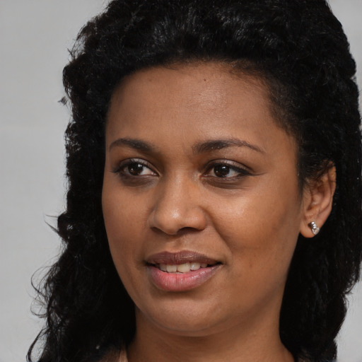 Joyful black young-adult female with long  black hair and brown eyes