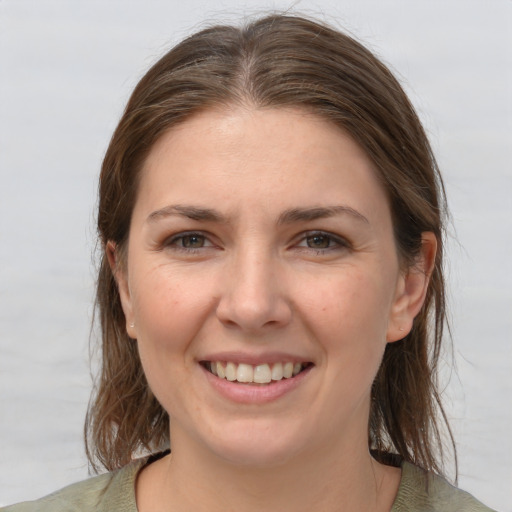 Joyful white young-adult female with medium  brown hair and grey eyes