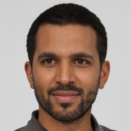 Joyful latino young-adult male with short  black hair and brown eyes