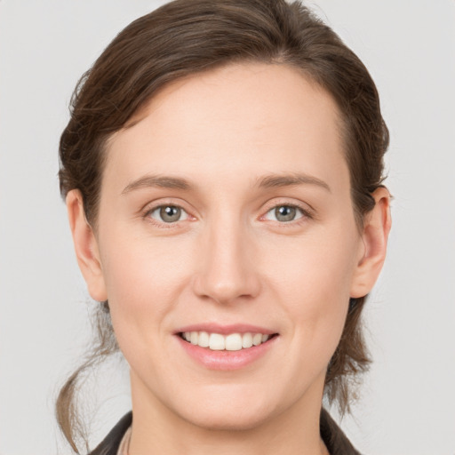 Joyful white young-adult female with medium  brown hair and grey eyes