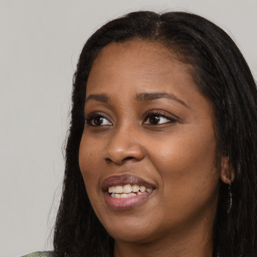Joyful black young-adult female with long  black hair and brown eyes