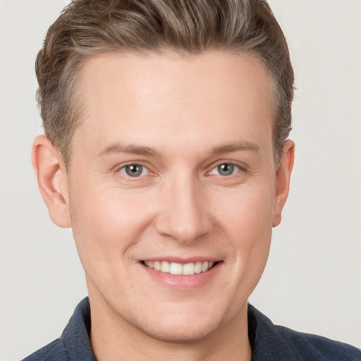 Joyful white young-adult male with short  brown hair and grey eyes