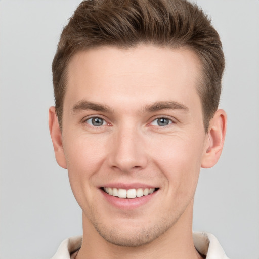 Joyful white young-adult male with short  brown hair and grey eyes