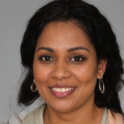 Joyful black young-adult female with long  black hair and brown eyes