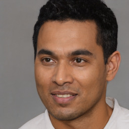 Joyful latino young-adult male with short  black hair and brown eyes