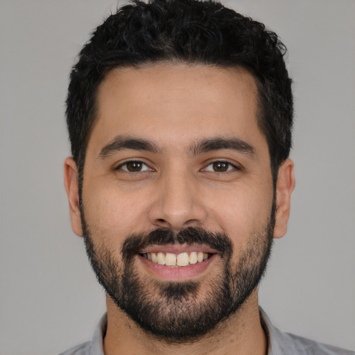 Joyful latino young-adult male with short  black hair and brown eyes