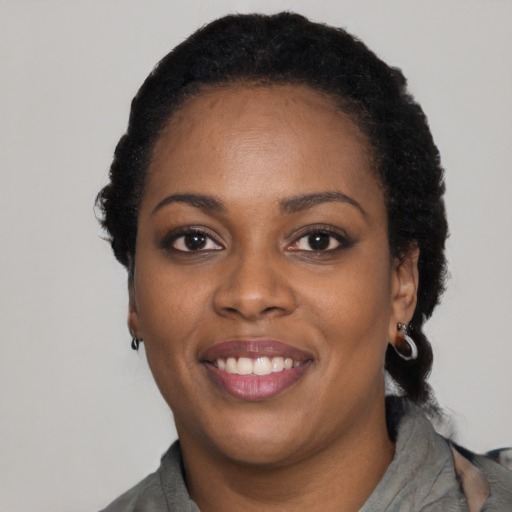 Joyful black young-adult female with long  black hair and brown eyes