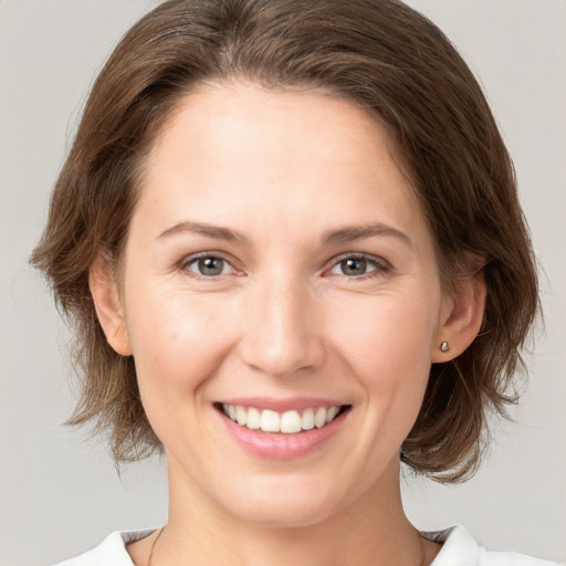 Joyful white young-adult female with medium  brown hair and grey eyes