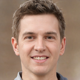 Joyful white young-adult male with short  brown hair and grey eyes