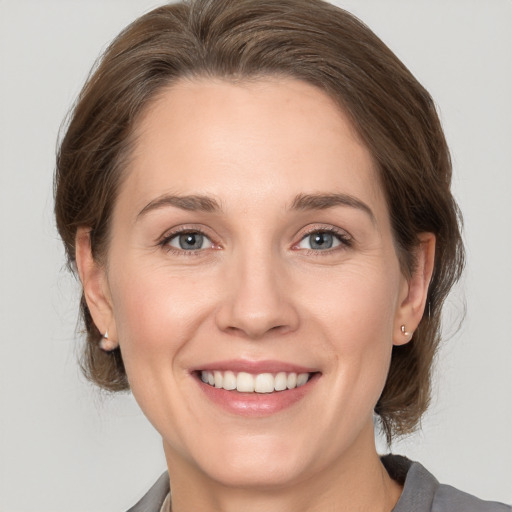 Joyful white adult female with medium  brown hair and grey eyes