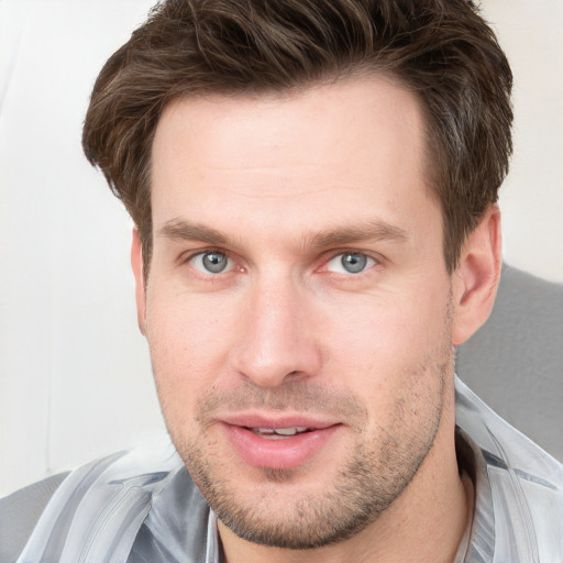 Joyful white young-adult male with short  brown hair and grey eyes