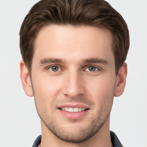 Joyful white young-adult male with short  brown hair and grey eyes