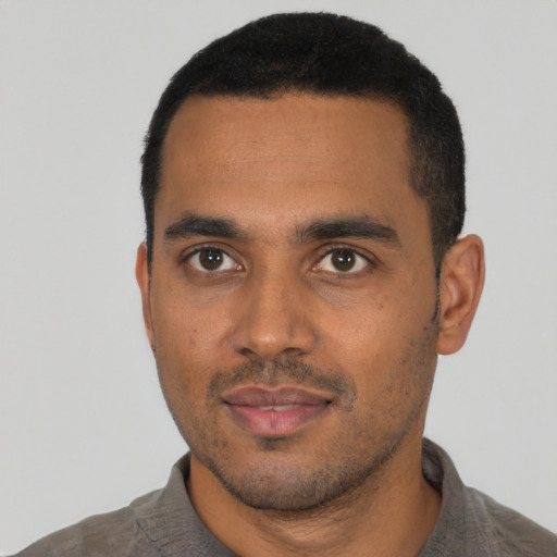 Joyful black young-adult male with short  black hair and brown eyes