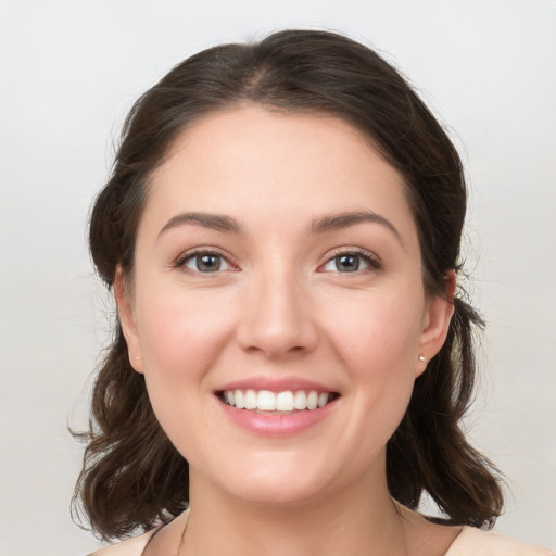 Joyful white young-adult female with medium  brown hair and grey eyes