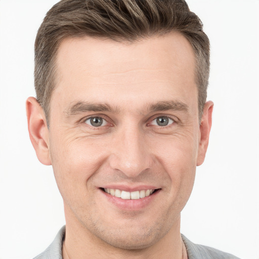 Joyful white young-adult male with short  brown hair and grey eyes