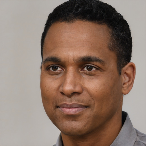 Joyful black young-adult male with short  black hair and brown eyes