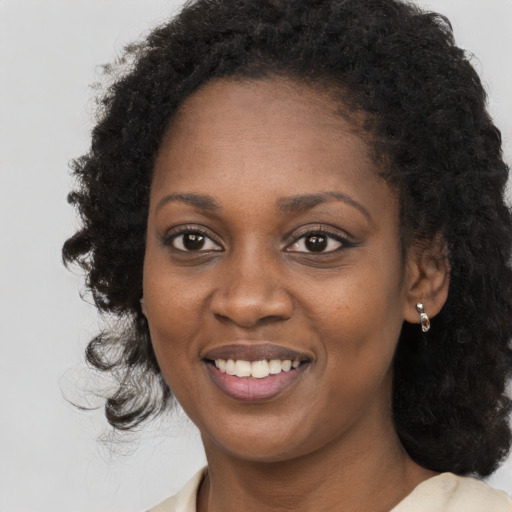 Joyful black young-adult female with long  black hair and brown eyes