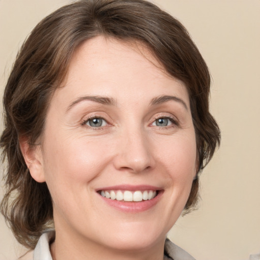 Joyful white young-adult female with medium  brown hair and grey eyes