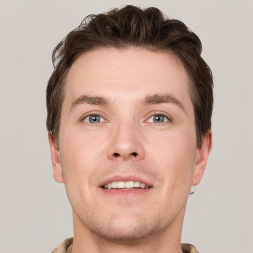 Joyful white young-adult male with short  brown hair and grey eyes