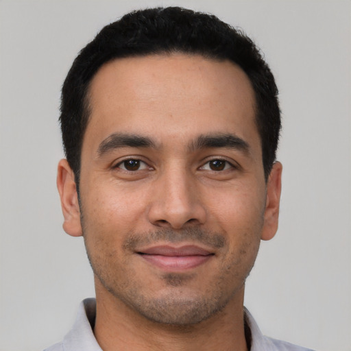 Joyful latino young-adult male with short  black hair and brown eyes