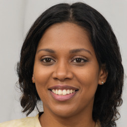 Joyful black young-adult female with long  brown hair and brown eyes