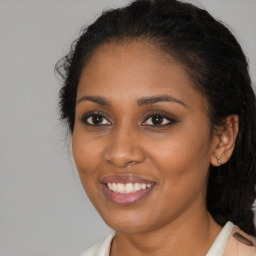 Joyful black young-adult female with long  brown hair and brown eyes