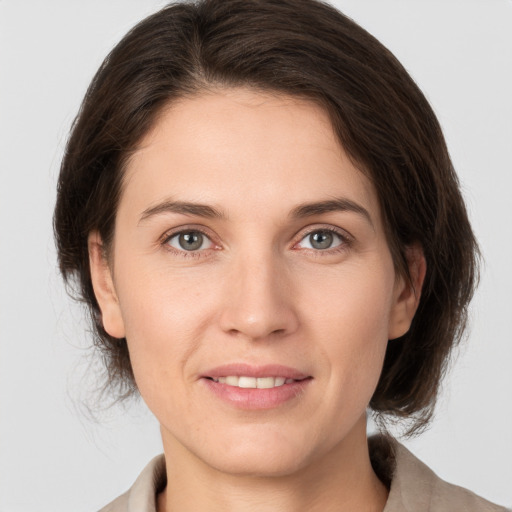 Joyful white young-adult female with medium  brown hair and grey eyes