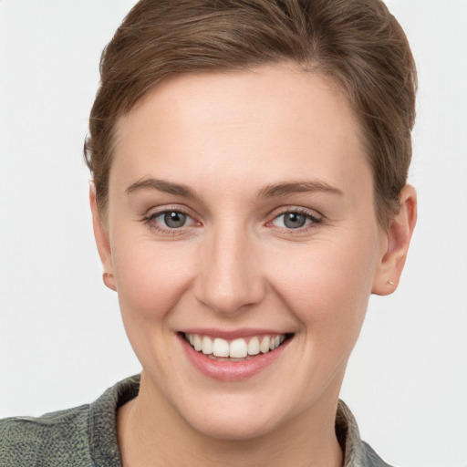 Joyful white young-adult female with short  brown hair and grey eyes