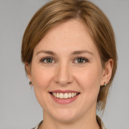 Joyful white young-adult female with medium  brown hair and grey eyes