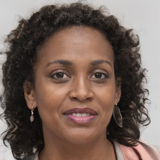 Joyful black young-adult female with long  brown hair and brown eyes