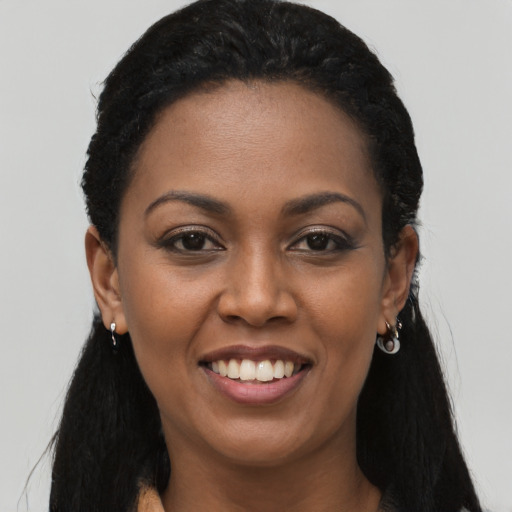 Joyful black young-adult female with long  black hair and brown eyes