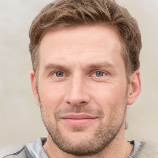 Joyful white young-adult male with short  brown hair and grey eyes