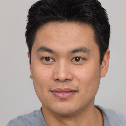 Joyful asian young-adult male with short  black hair and brown eyes