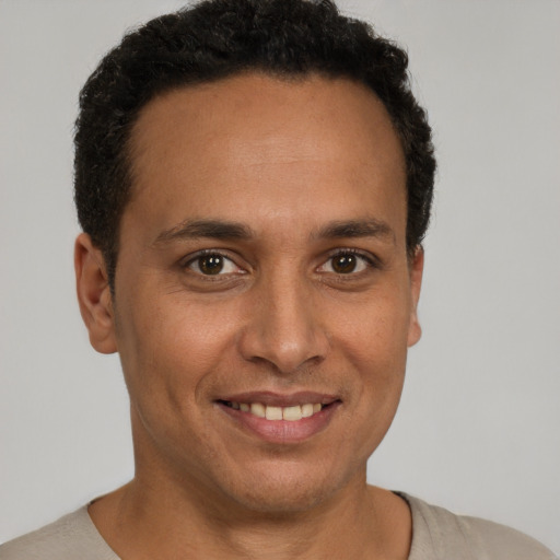 Joyful latino young-adult male with short  brown hair and brown eyes