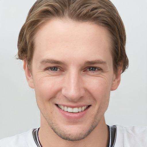 Joyful white young-adult male with short  brown hair and grey eyes